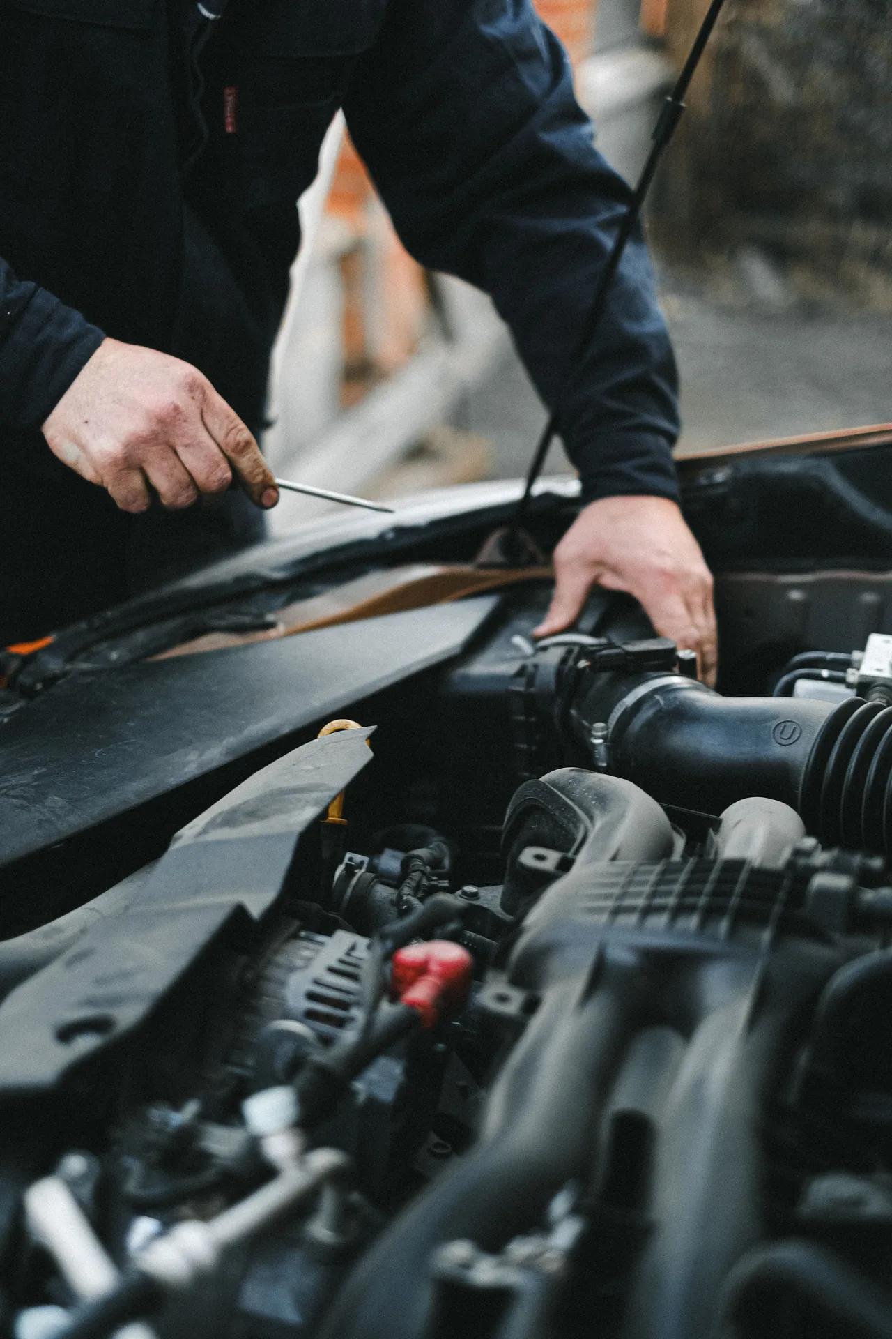 Illustrative photograph of hands working beside a vehicle’s air intake