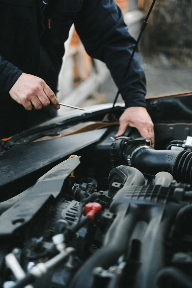 Illustrative photograph of hands working beside a vehicle’s air intake